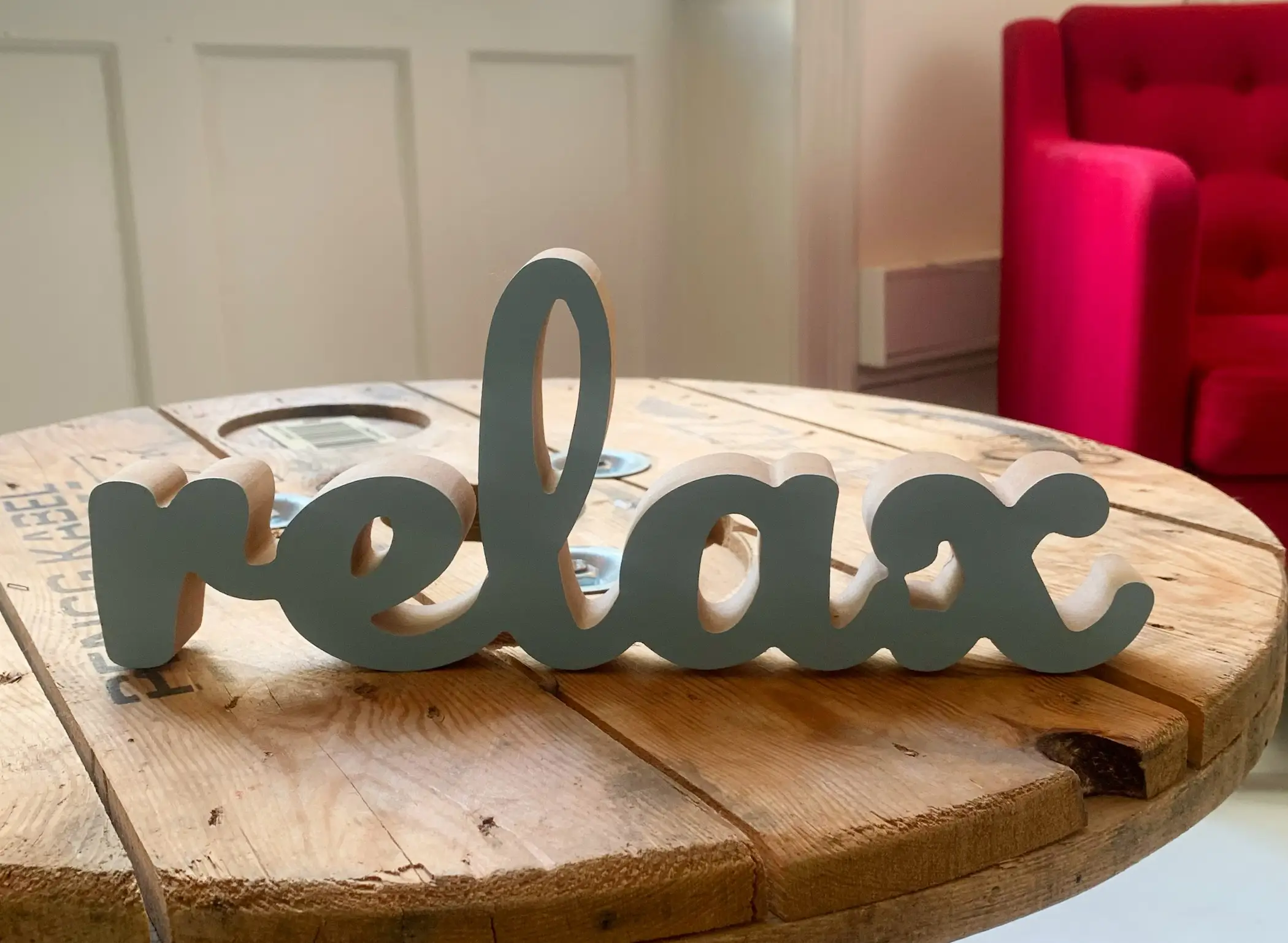 Træbord med dekorativt “relax”-skilt i klinikmiljø hos Be Relaxed i København, brugt i sektion om massageordning for virksomheder.